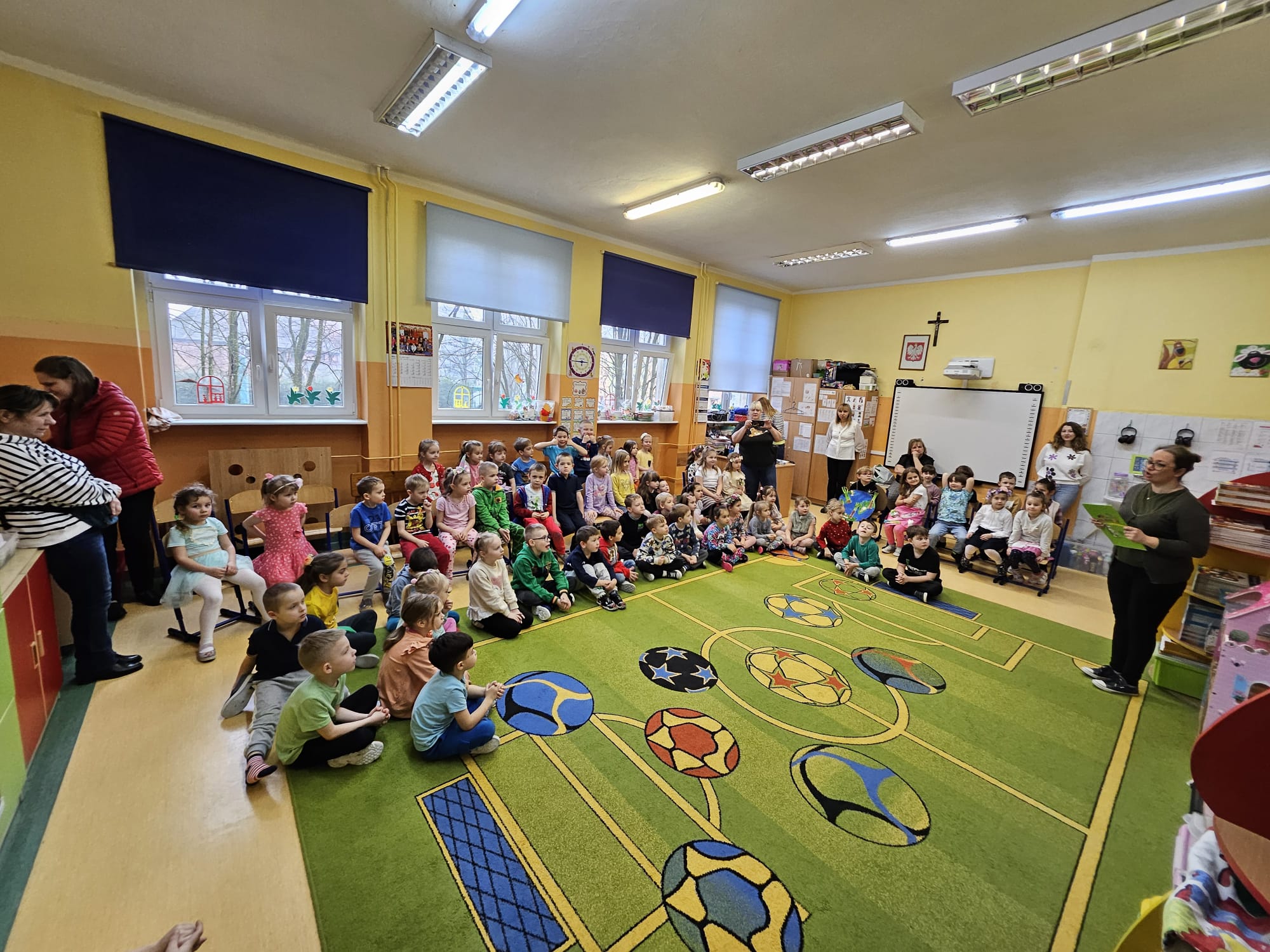 uczniowie przedszkola na dywanie we wzór boiska do piłki nożnej